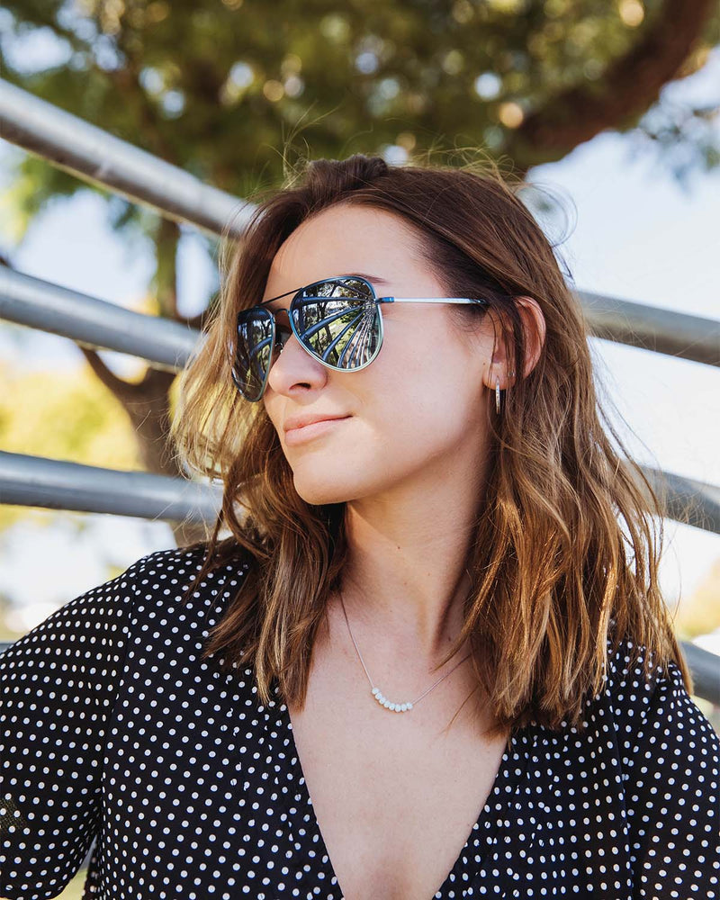 Woman wearing a black and white polka dot shirt and black frame sunglasses.
