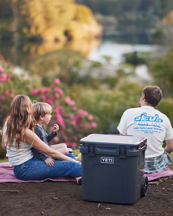 a family of three having a picnic with a wheeled YETI cooler