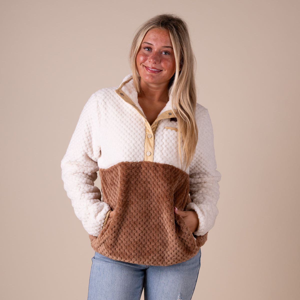 Woman wearing a white and brown fleece pullover against a beige background