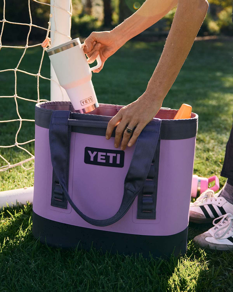 Woman putting a white yeti cup into a purple yeti camino bag.