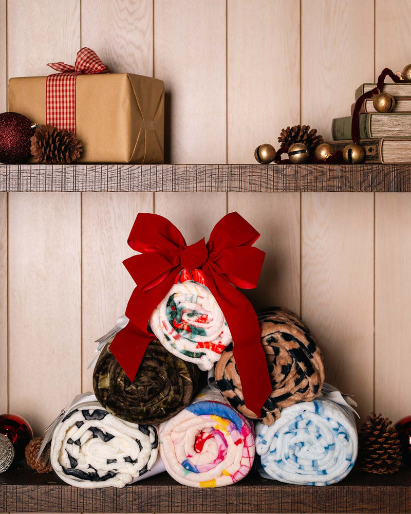 blankets stacked in the shape of a christmas tree with a bow on top.