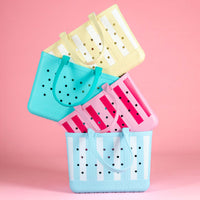 Four colorful laundry baskets with handles on a pink background