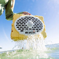 Person pulling a yellow turtlebox out of the water.