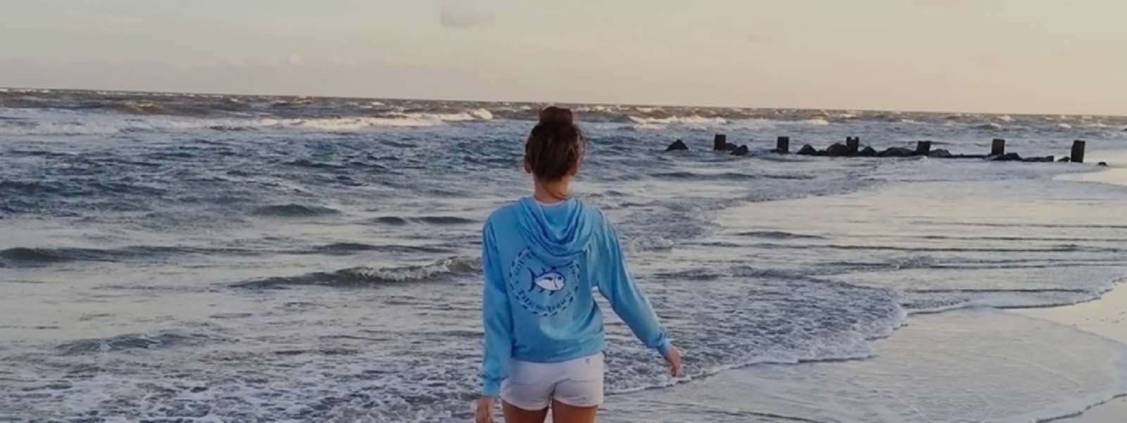 Guy wearing a Southern Tide t-shirt watches the sunset from the beach.