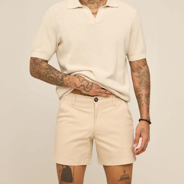 Person wearing a beige polo shirt and shorts against a plain background