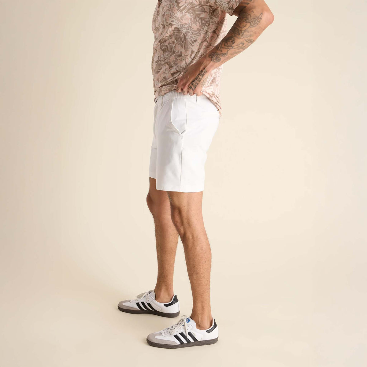 Person wearing white shorts and Adidas shoes on a beige background
