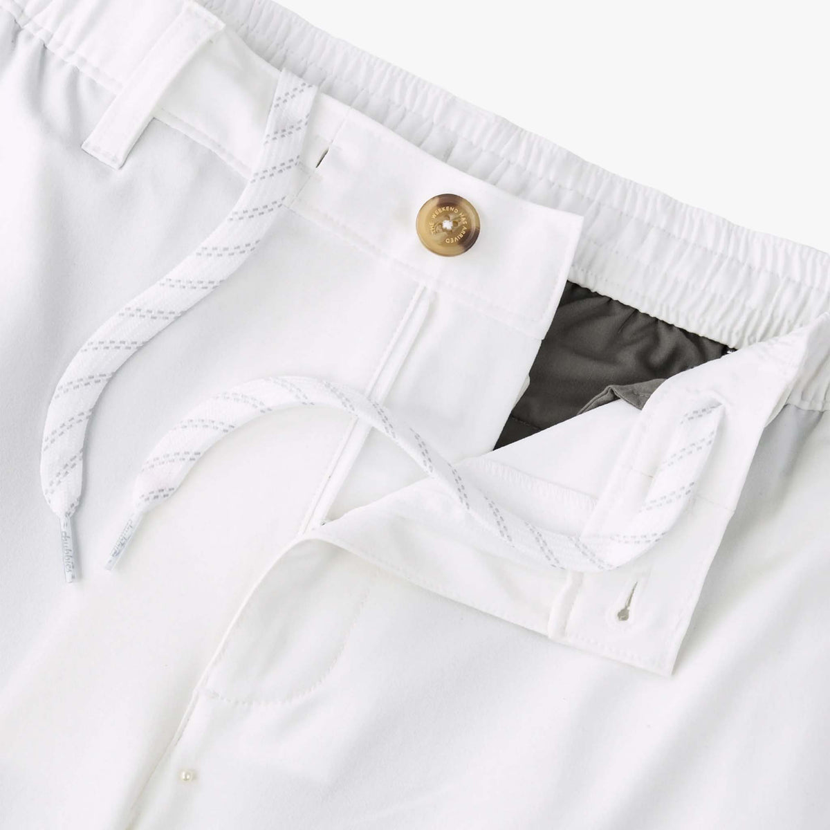 Close-up of white shorts with a button and waistband detail.