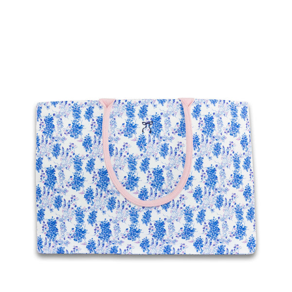 Floral-patterned bag with pink handles on a white background
