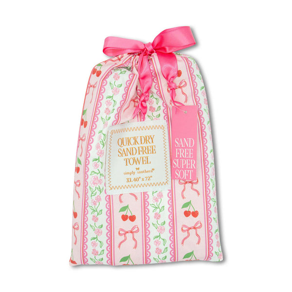 Patterned Pouch with pink bows and red cherry hearts containing a quick dry sand free towel measuring 40"x72" by Simply Southern