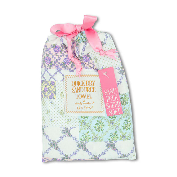 Patterned Pouch with purple floral patches containing a quick dry sand free towel measuring 40"x72" by Simply Southern