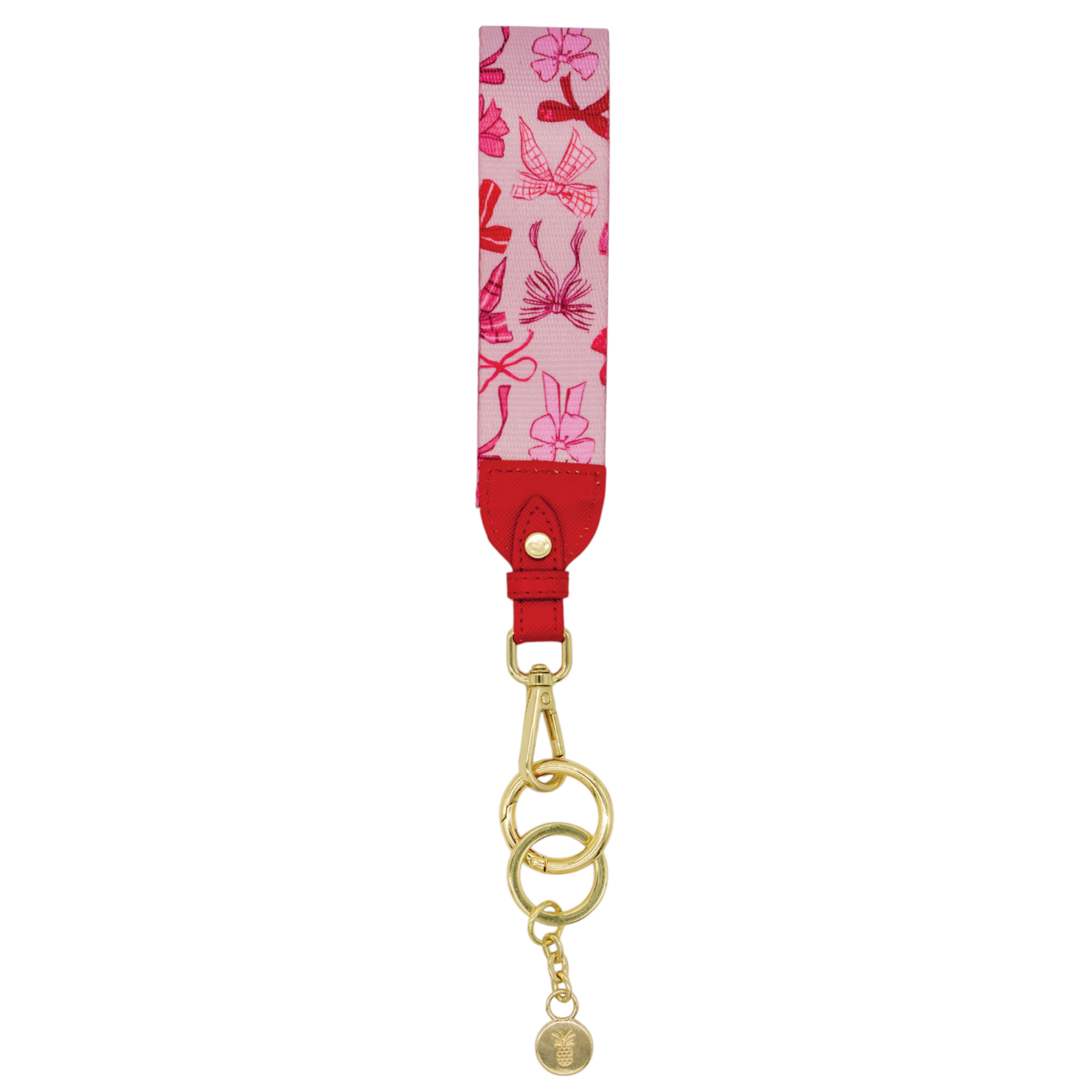 Pink key fob with red bow print, red leather accent, and gold hardware featuring clasp, key rings, and small charm.