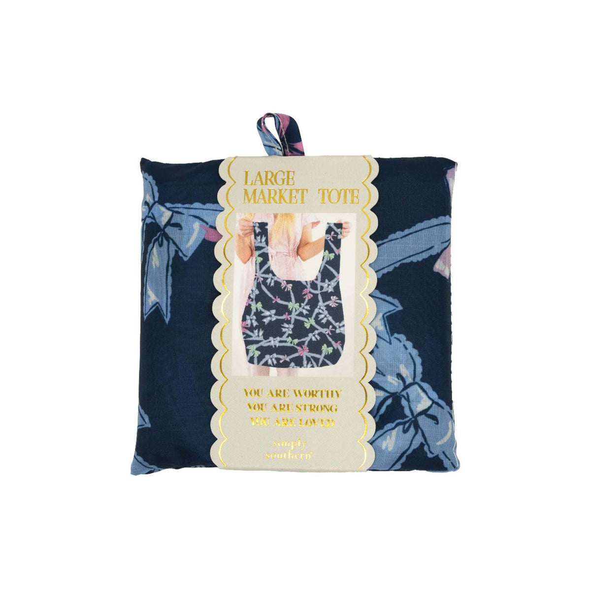 Simply Southern Large Market Tote in navy ribbon print with colorful bow accents, shown folded in packaging with gold scalloped label and inspirational quote.