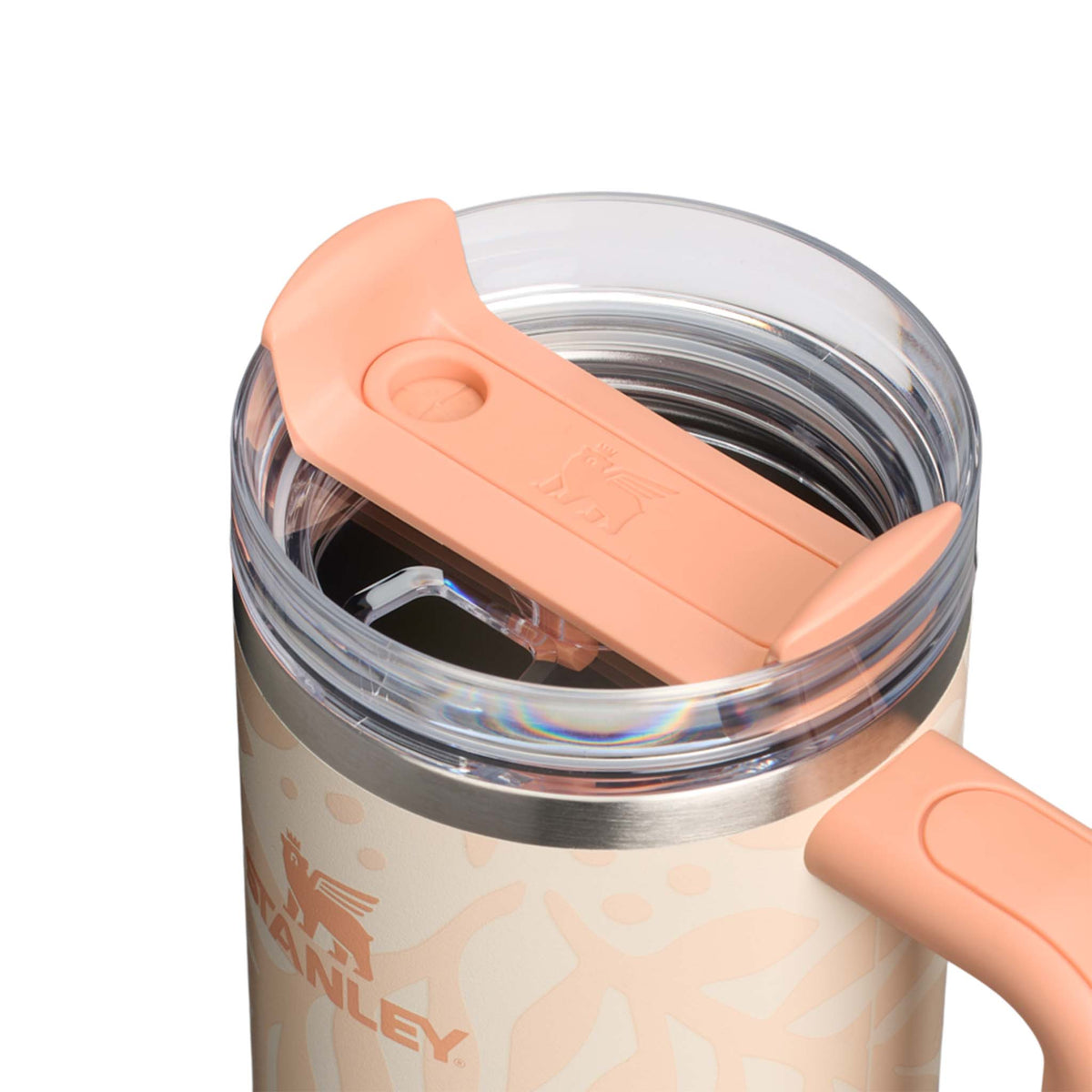Stanley tumbler with peach-colored lid and handle on a white background