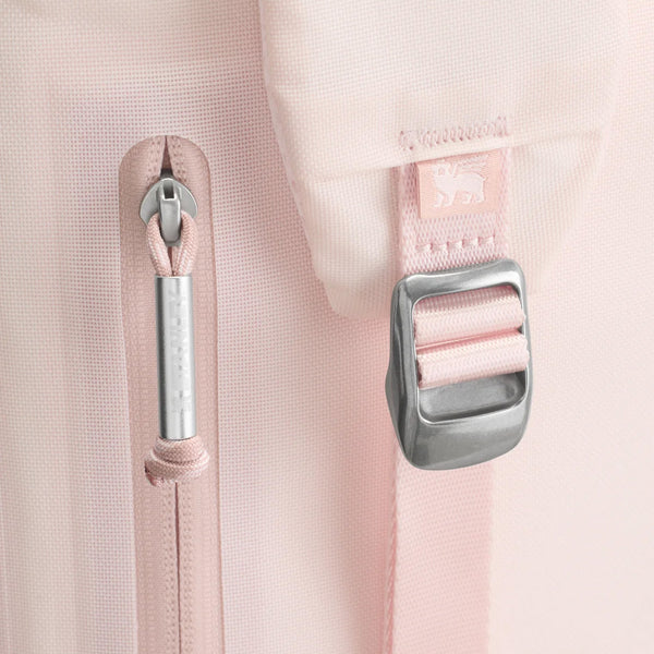 The cooler features a soft pink exterior, adjustable padded backpack straps, a front zippered pocket, and a top handle. Designed for portability and insulation, it is photographed in a studio with a neutral background.