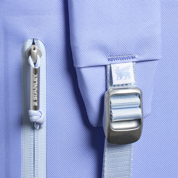 The cooler features a soft purple exterior, adjustable padded backpack straps, a front zippered pocket, and a top handle. Designed for portability and insulation, it is photographed in a studio with a neutral background.