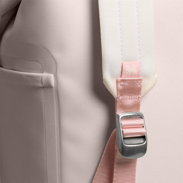 The compact cooler features a soft pink exterior, adjustable padded backpack straps, a front zippered pocket, and a top carry handle. Designed for lightweight portability and insulation.