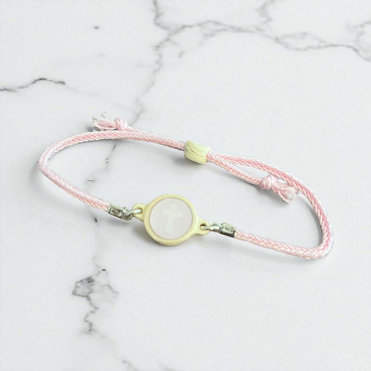 Pink braided bracelet with a yellow clasp on a marble surface