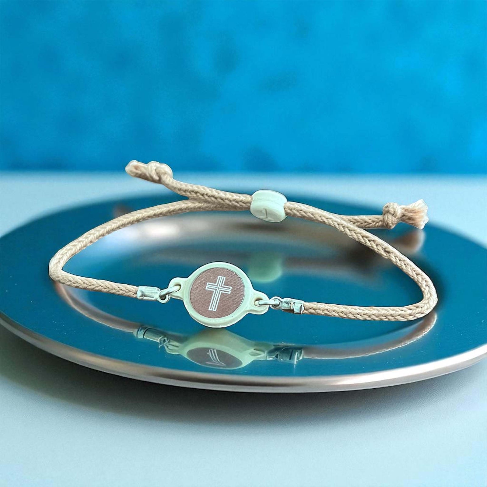 Bracelet with a cross charm on a blue plate against a blue background
