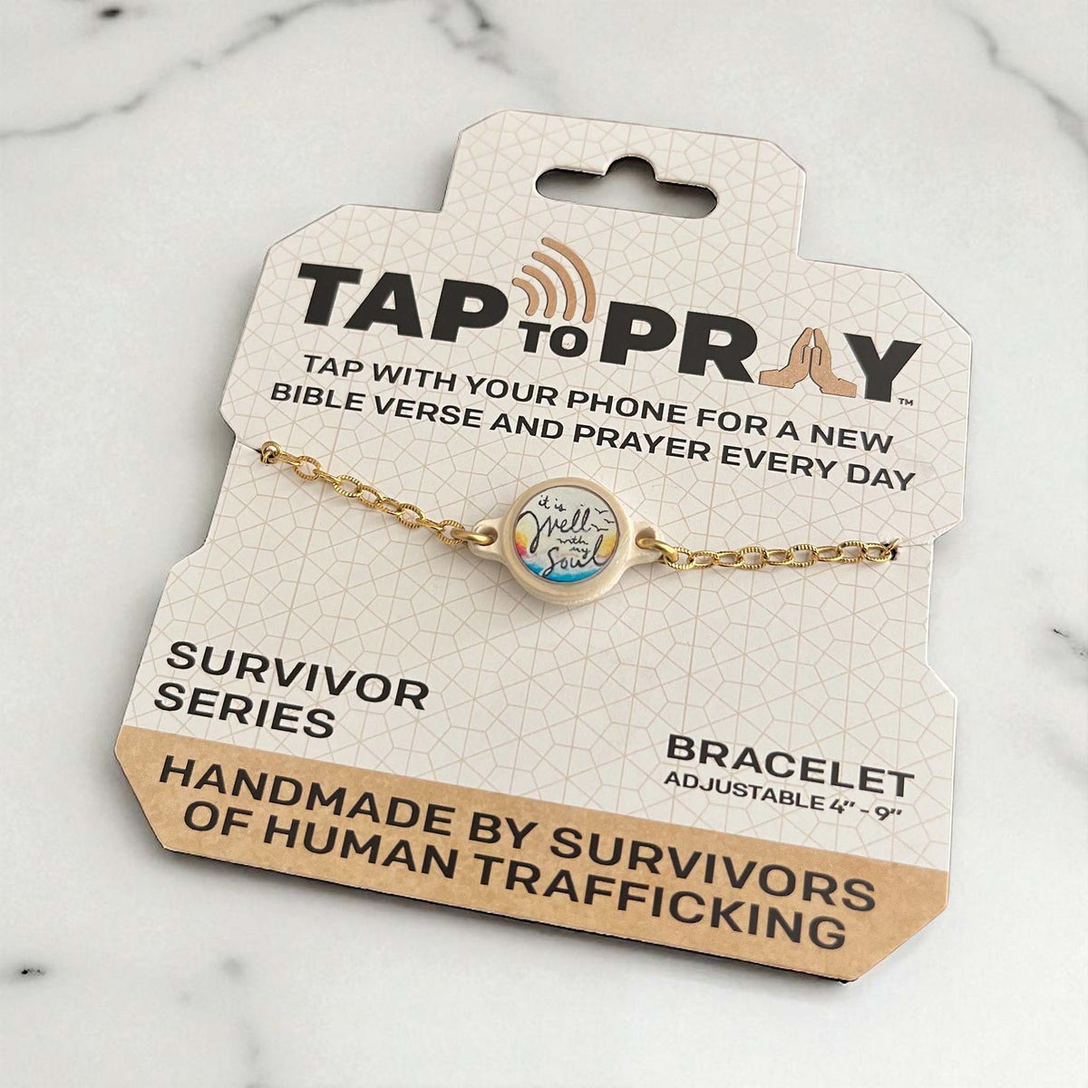 Gold bracelet on a 'Tap to Pray' packaging with text about prayer and human trafficking survivors.