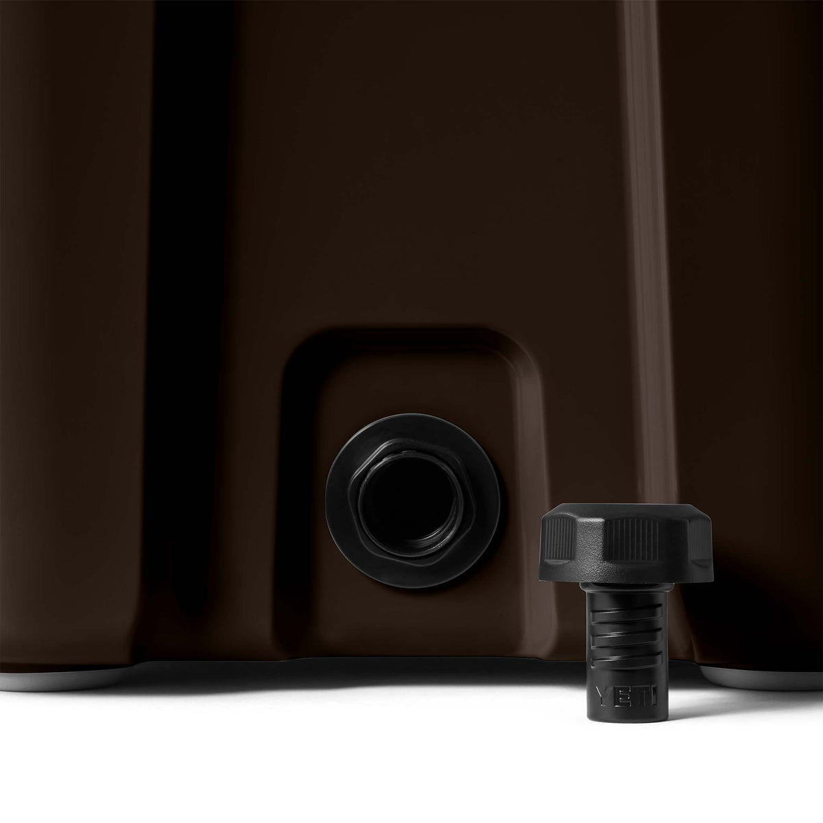 Close-up of cooler’s drain plug and base, showing black plug removed and placed beside the opening.