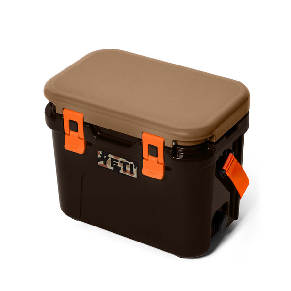 Angled side view of the YETI Roadie 15 Hard Cooler in Wetlands Camo showing carry strap and camo YETI logo.