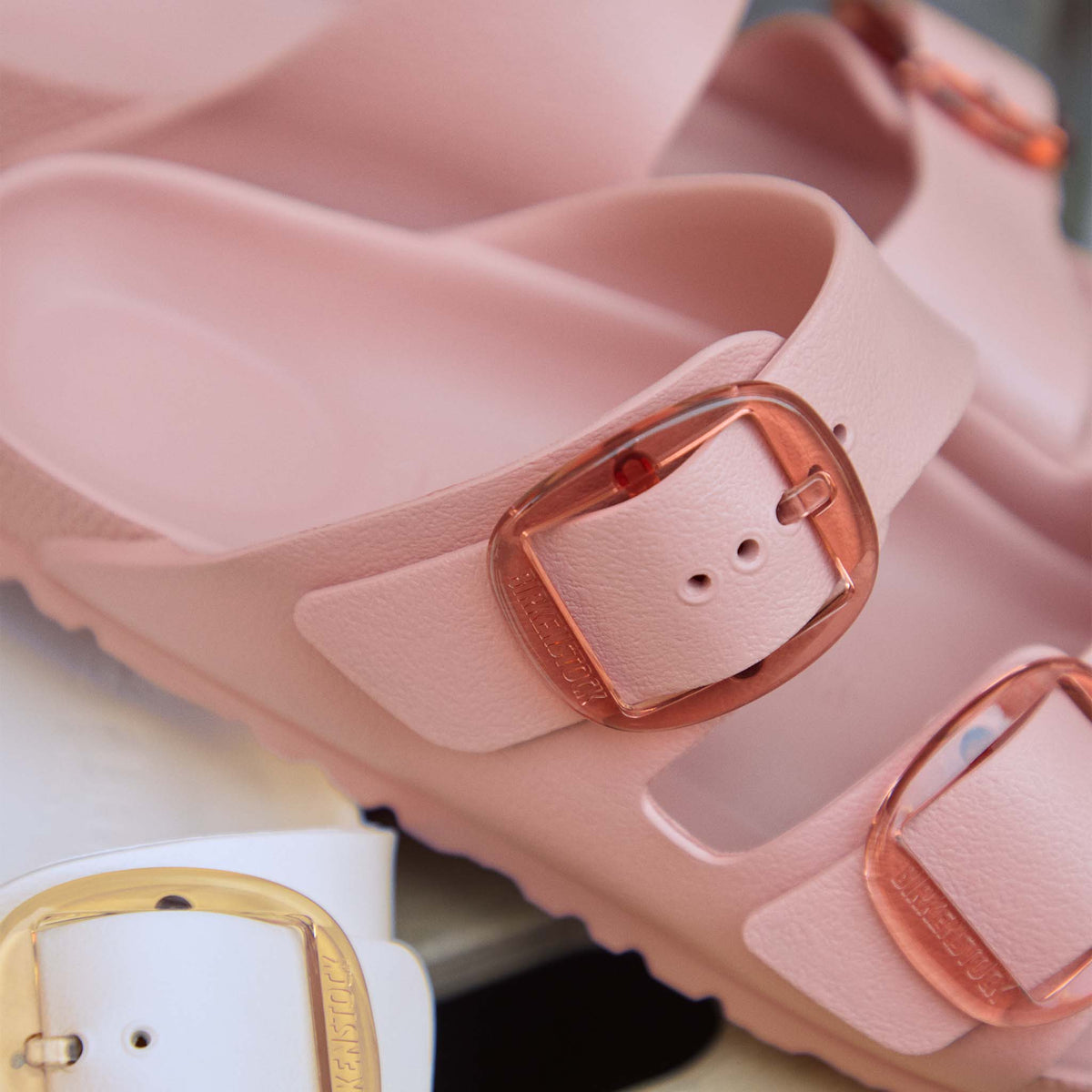 Close-up detail of Birkenstock Arizona EVA sandal in Pink Clay showing textured strap and translucent oversized buckle hardware.