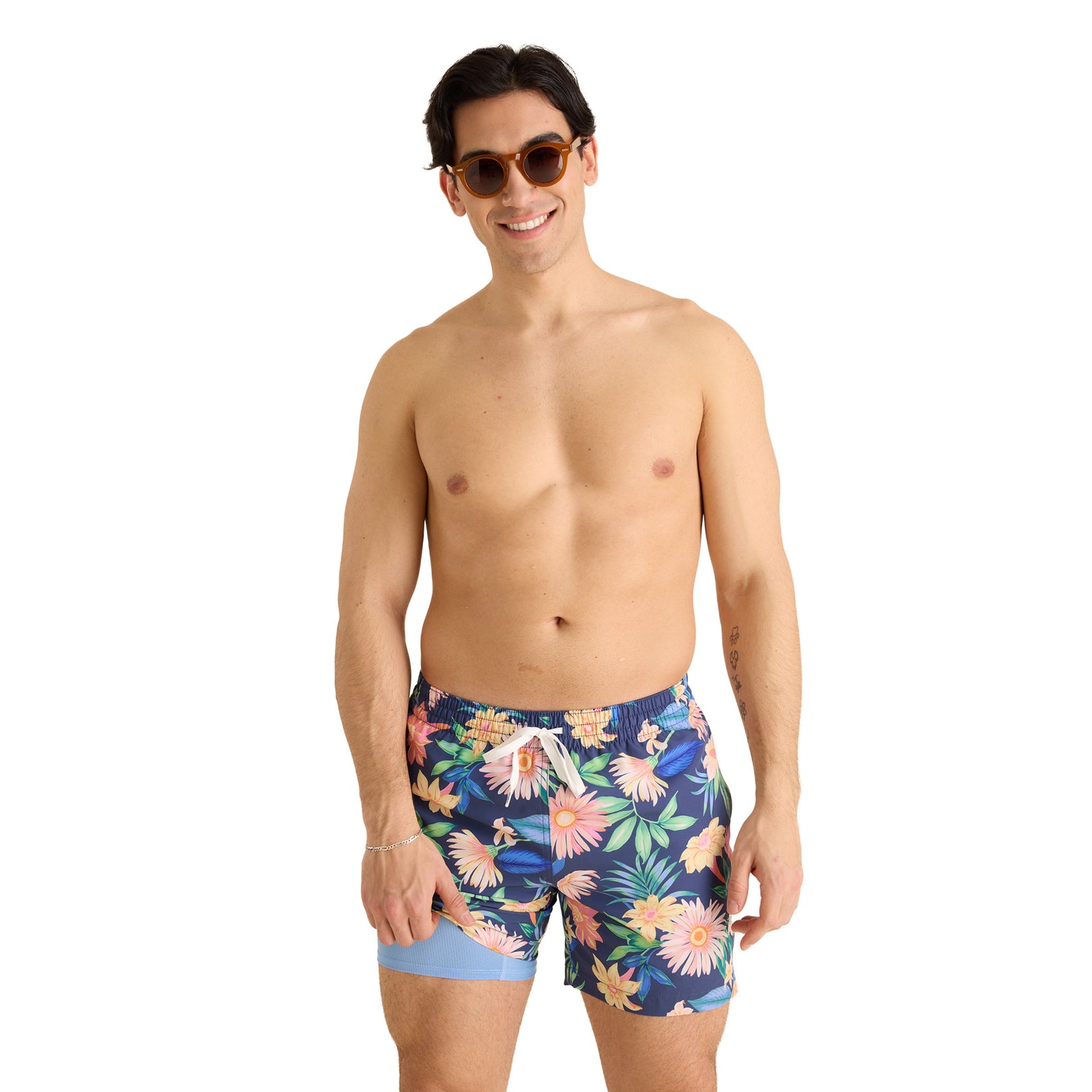 Man wearing colorful floral swim shorts by Chubbies on a white background