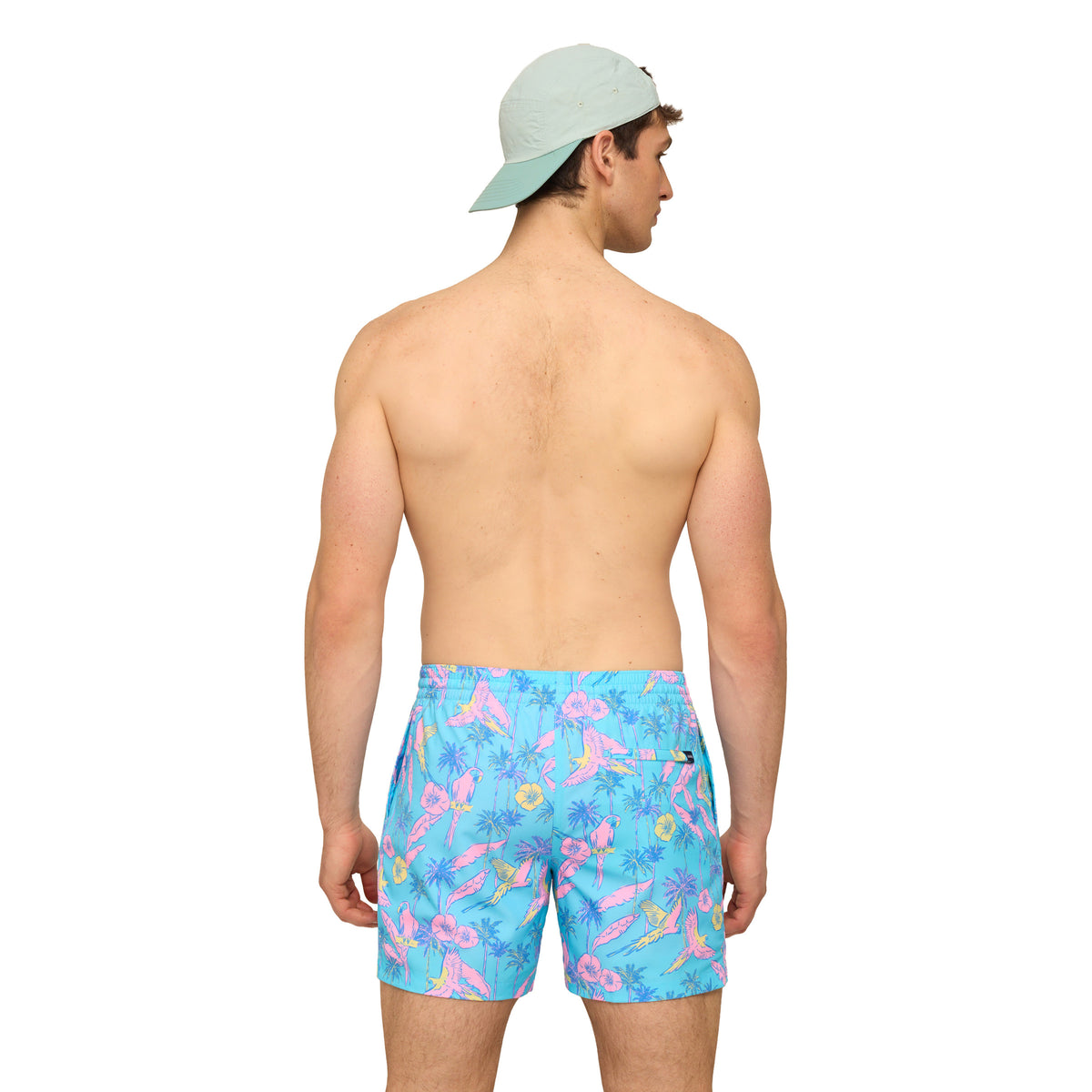 Man wearing turquoise blue swim shorts with all over pink and yellow bird pattern in front of a white background.
