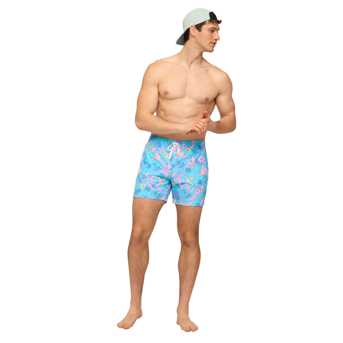 Man wearing turquoise blue swim shorts with all over pink and yellow bird pattern in front of a white background.