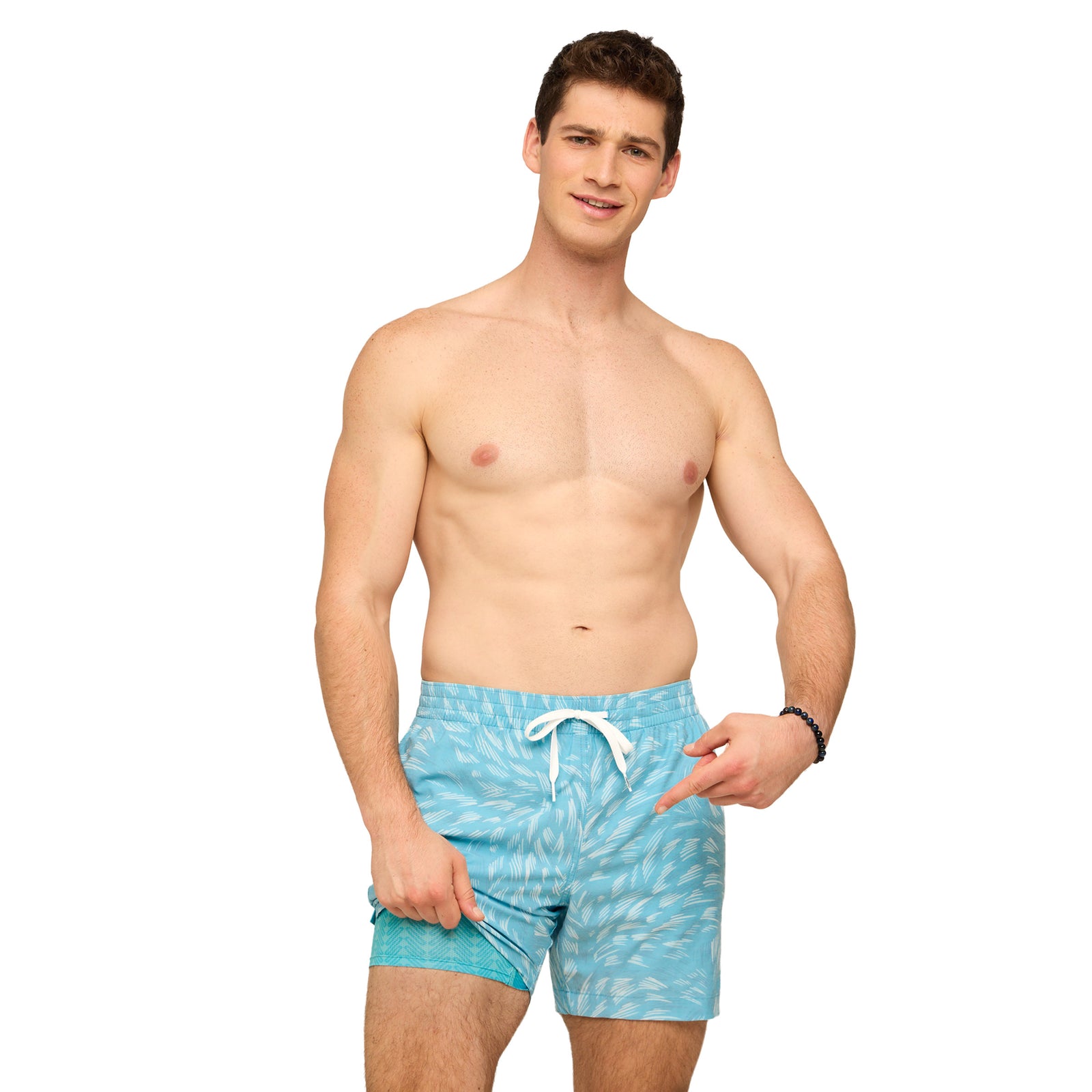 Man wearing turquoise blue swim shorts with a subtle feather-like all -over pattern on a white background
