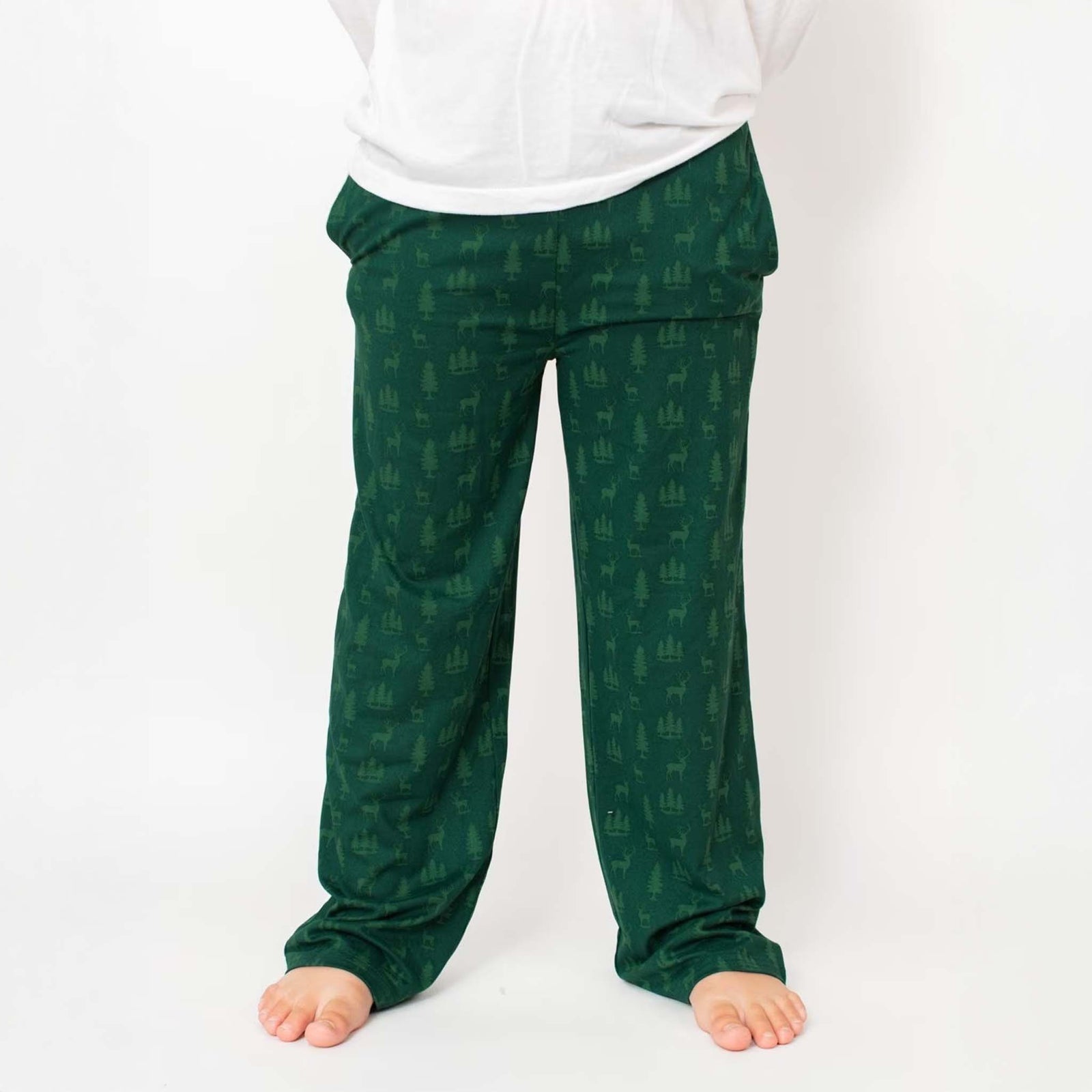Green pajama pants with woodland deer and tree print, shown worn with white top.