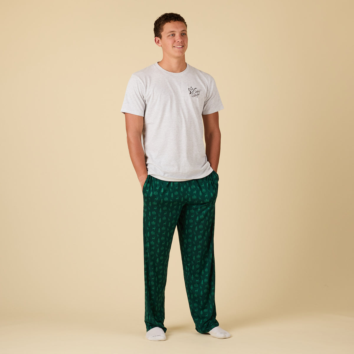 Man wearing a white t-shirt and green patterned pants on a beige background