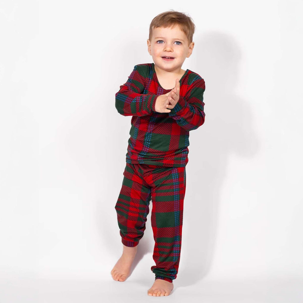 Child wearing red and green plaid pajamas on a white background