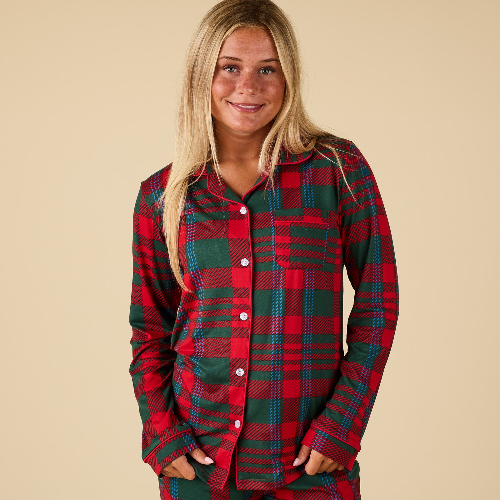 Person wearing a red and green plaid pajama set on a beige background