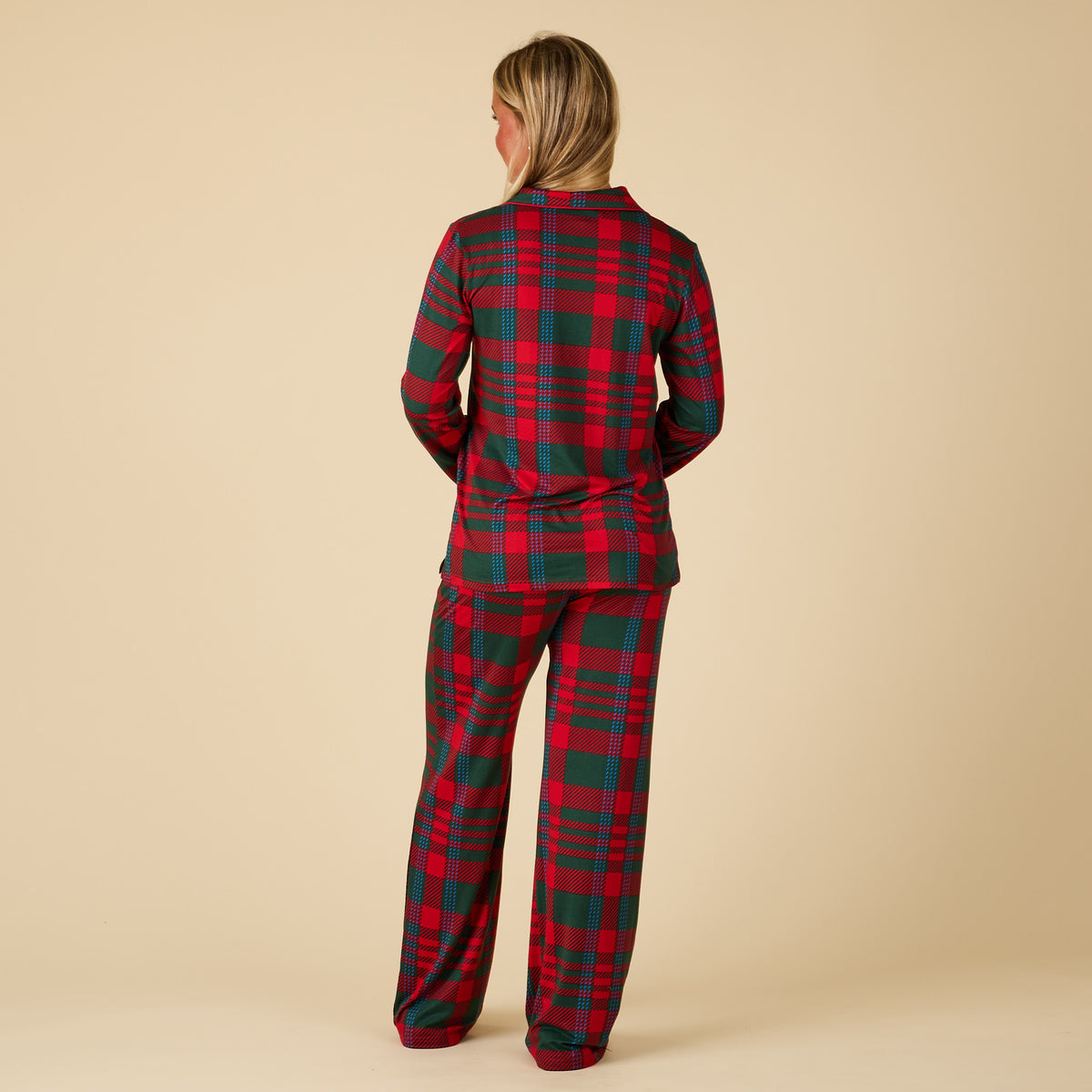 Person wearing a red and green plaid pajama set on a beige background