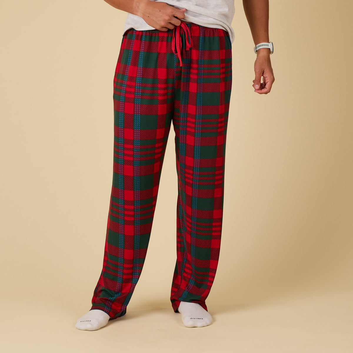 Red and green plaid pajama pants worn by a person on a beige background