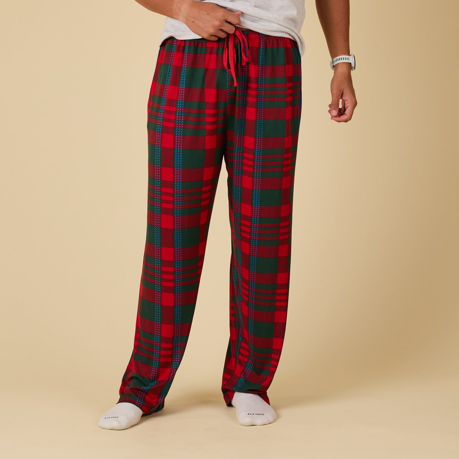 Red and green plaid pajama pants worn by a person on a beige background