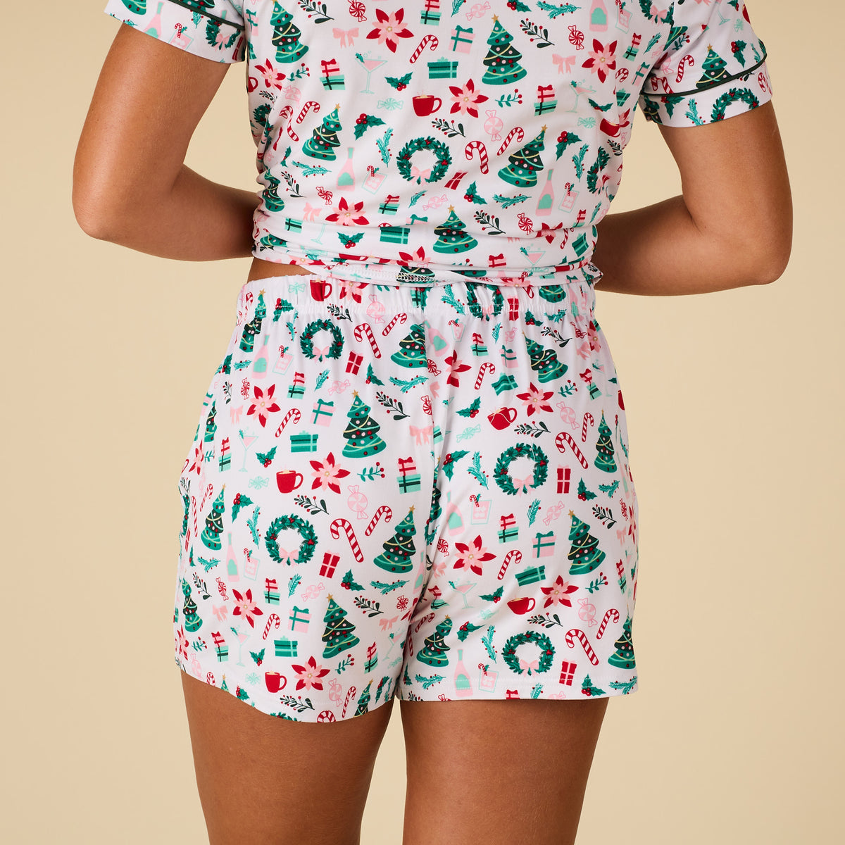 Holiday-themed outfit with a pattern of trees, wreaths, and candy canes on a beige background.