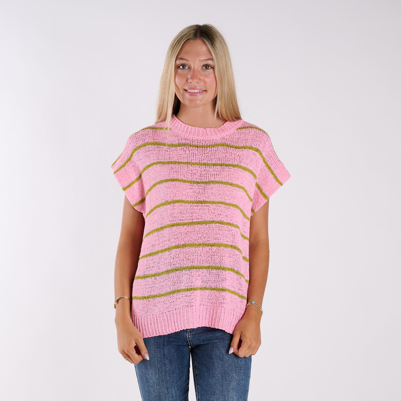 Pink | Woman wearing a pink and green striped sweater against a white background