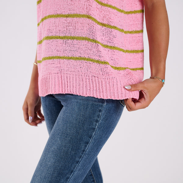  Person wearing a pink knitted sweater with green stripes and blue jeans on a light gray background