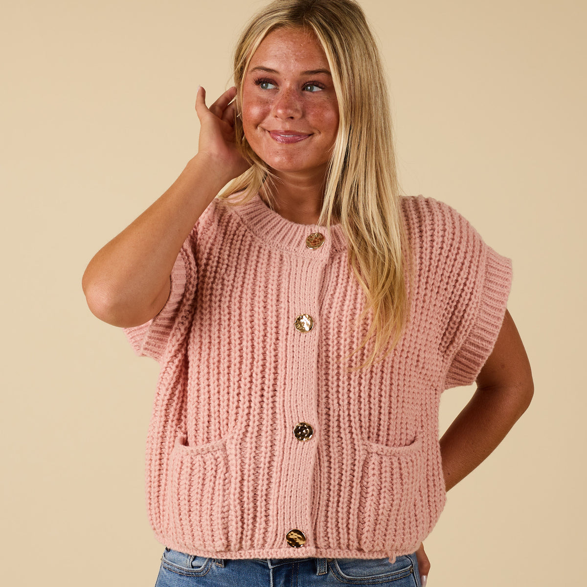 Front view of women’s blush chunky knit short sleeve button-front top with gold buttons and front pockets.
