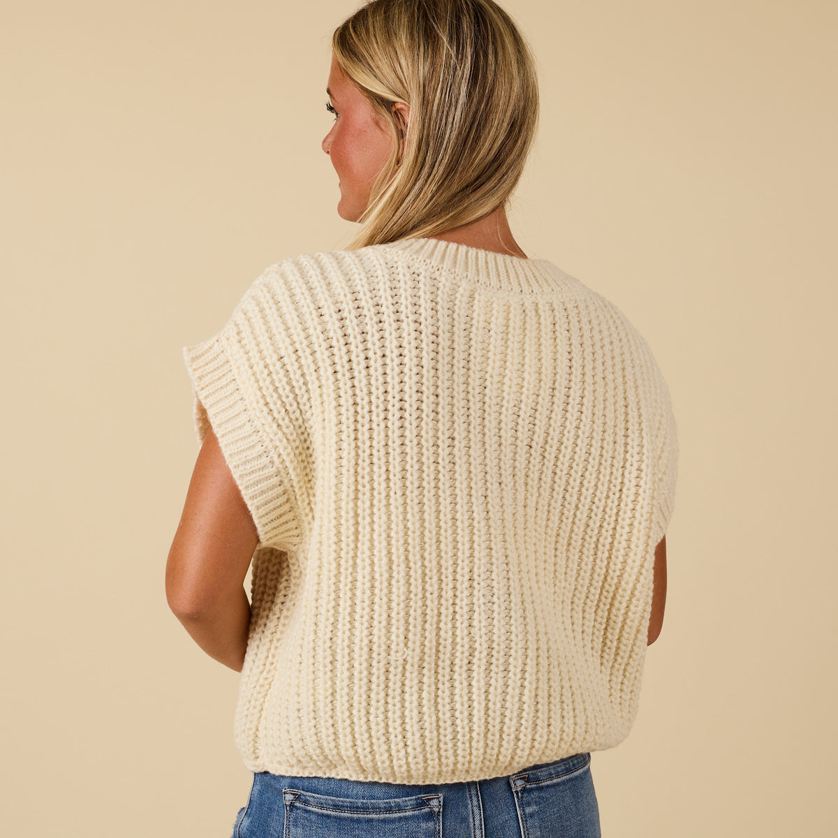 Back view of women’s cream chunky knit short sleeve button-front top with ribbed texture.