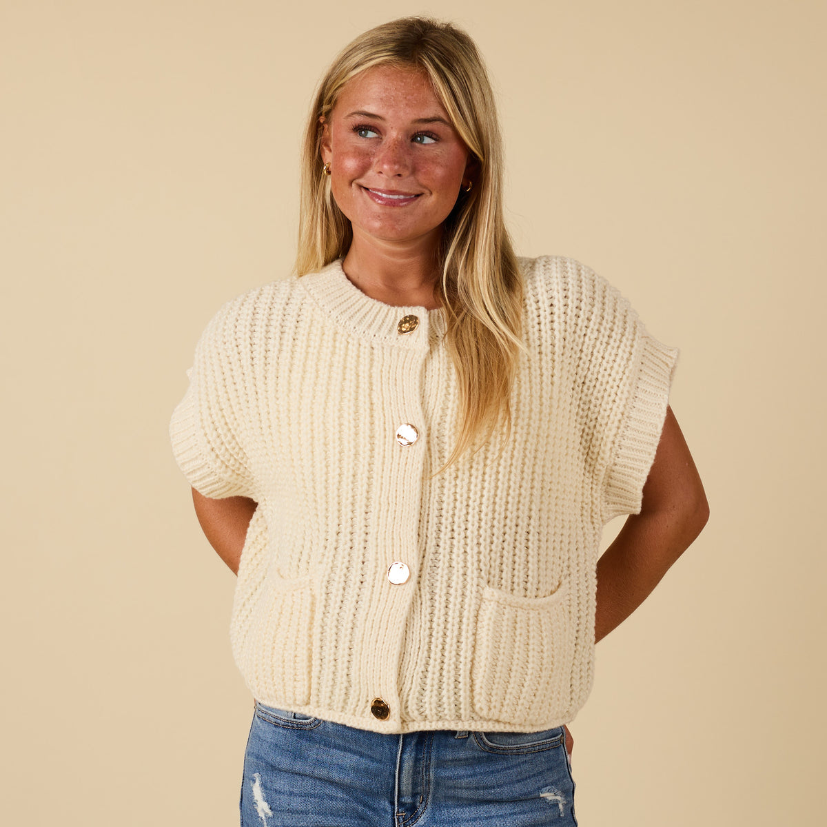 Front view of women’s cream chunky knit short sleeve button-front top with gold buttons and patch pockets.