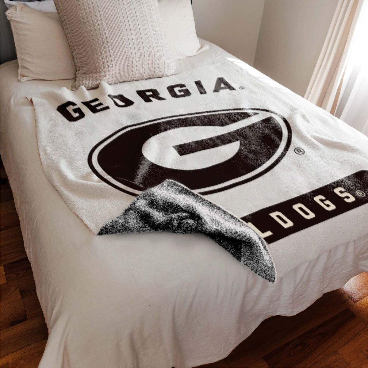Blanket with 'Georgia Bulldogs' logo draped over a bed