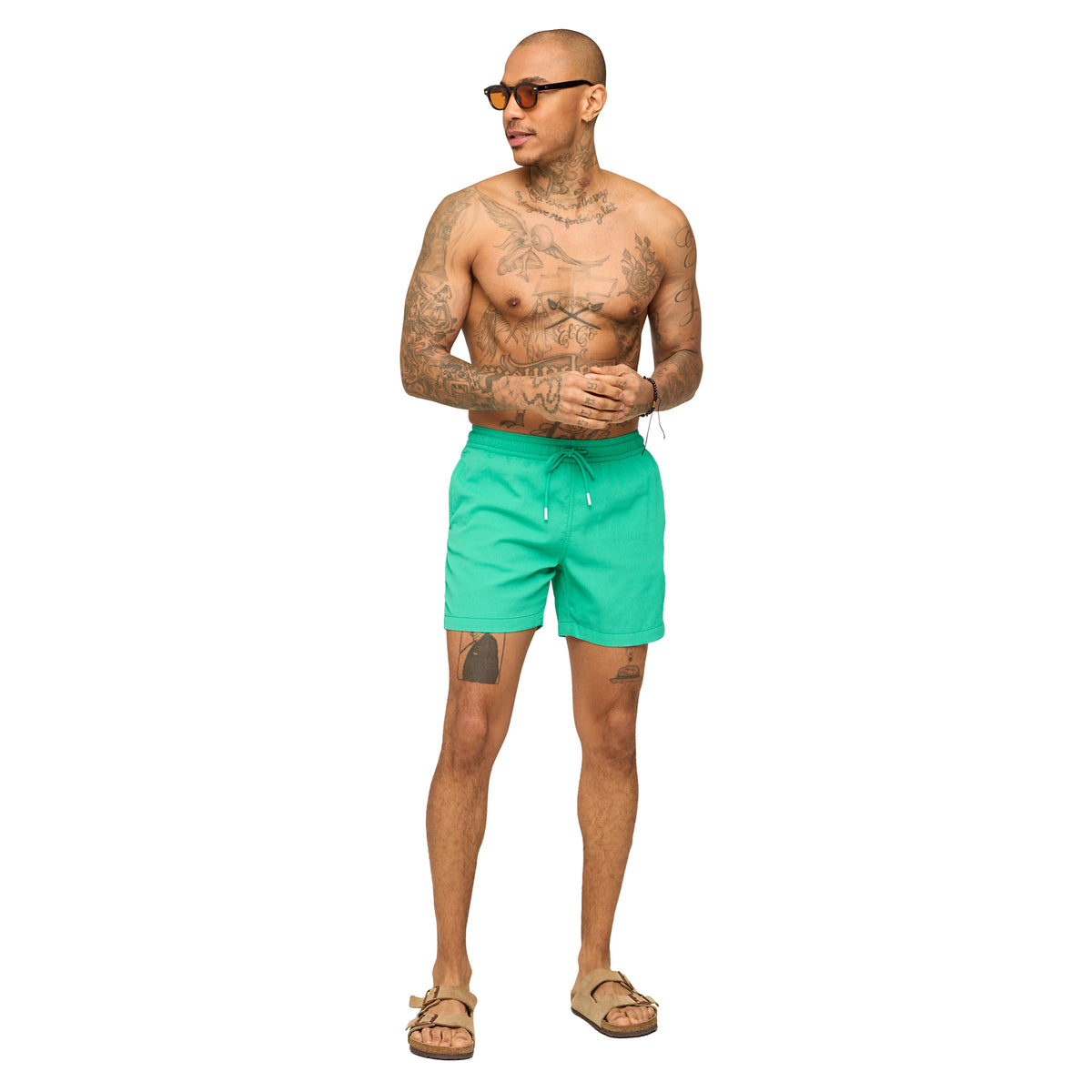 Man wearing teal Chubbies swim shorts standing in front of a white background