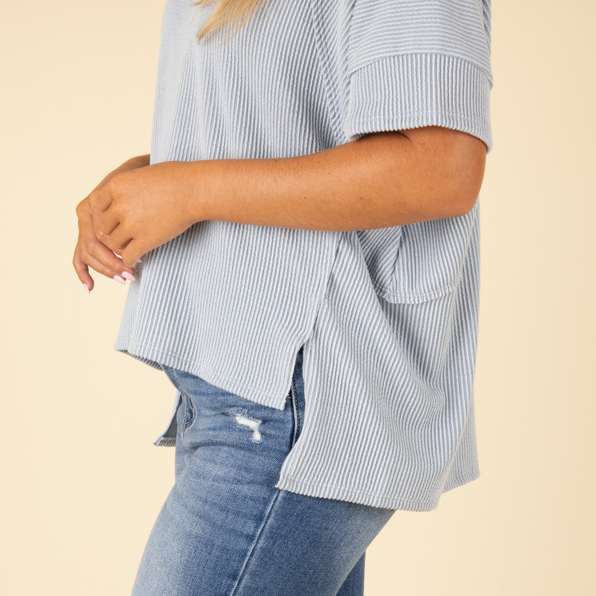 Person wearing a blue top and jeans on a beige background