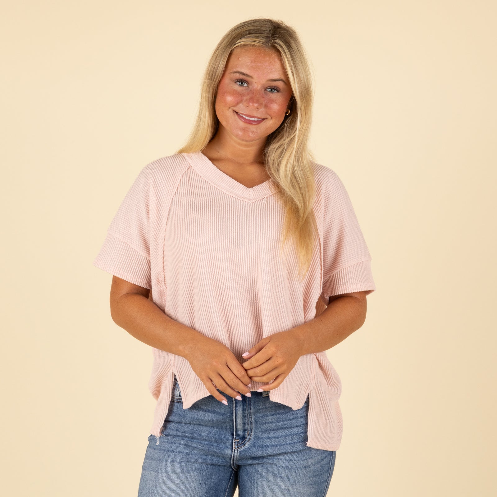 Woman wearing a pink shirt and blue jeans on a beige background