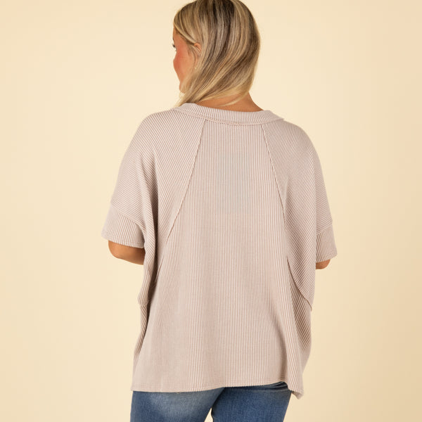 Woman wearing a beige ribbed top on a beige background