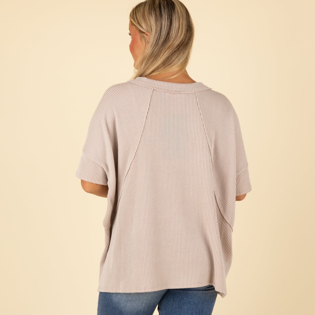 Woman wearing a beige ribbed top on a beige background