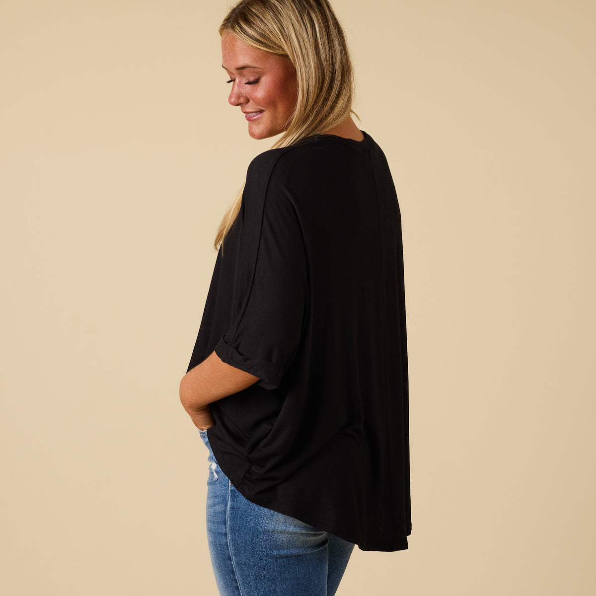 Model wearing hi lo black short sleeve top with relaxed fit, shown from back